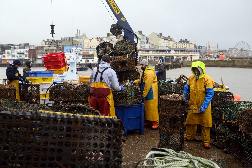 Des pêcheurs nettoient et réparent leurs casiers à homard alors qu'ils se préparent pour leur prochain voyage en mer, sur la jetée sud du port de pêche du port de Bridlington, au nord-est de l'Angleterre, le 11 décembre 2020. (AFP)