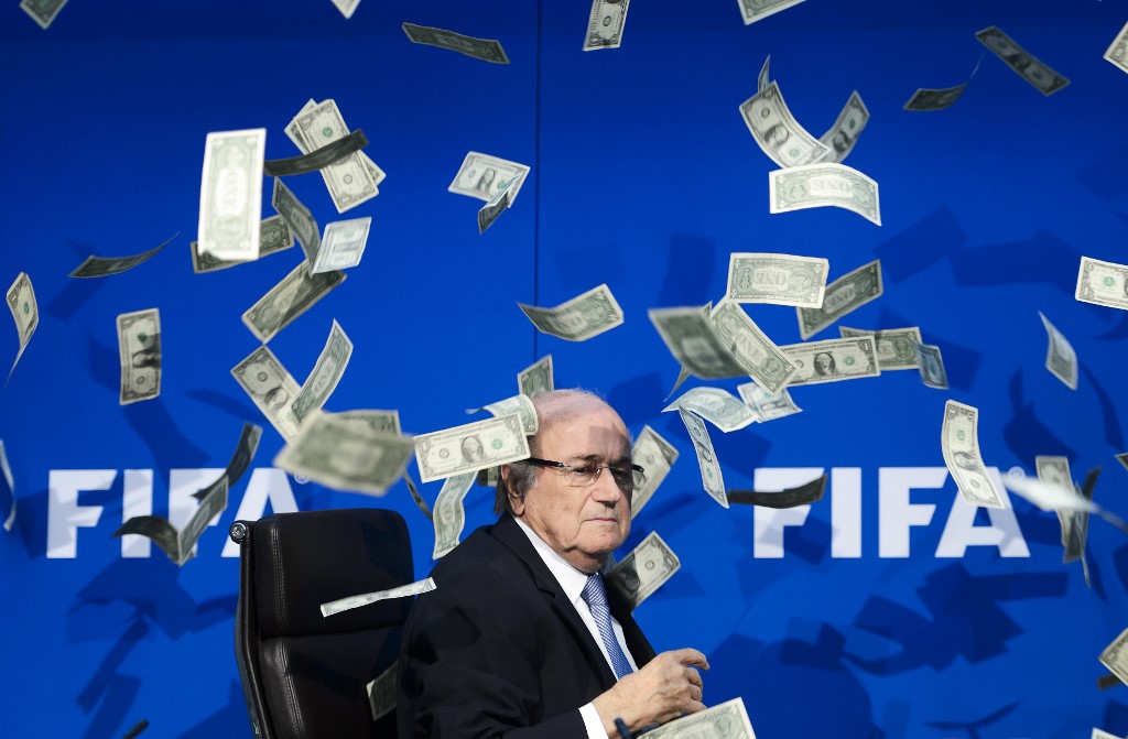 Sepp Blatter, entouré de faux billets en dollars, lancés par un comédien britannique lors d'une conférence de presse au siège de l'instance mondiale de la FIFA à Zurich. (AFP)