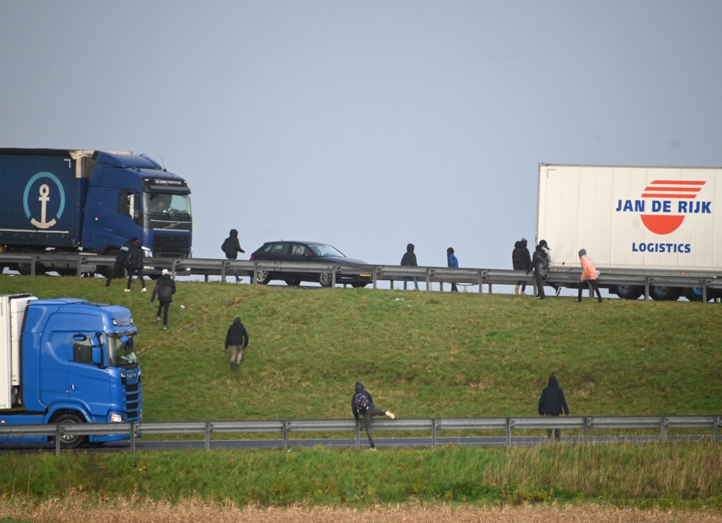 Les migrants attendent de monter à l'arrière des camions à destination du Royaume-Uni tandis que le trafic est arrêté en attendant de monter à bord des navettes à l'entrée du site du tunnel sous la Manche à Calais, dans le nord de la France, le 17 décembre 2020. (AFP)