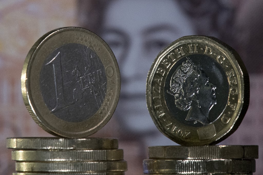 Dans cette photo prise le 14 décembre 2017, une pièce de monnaie britannique d'une livre sterling et une pièce d'un euro sont disposées devant un billet de dix livres sterling britanniques. (AFP)