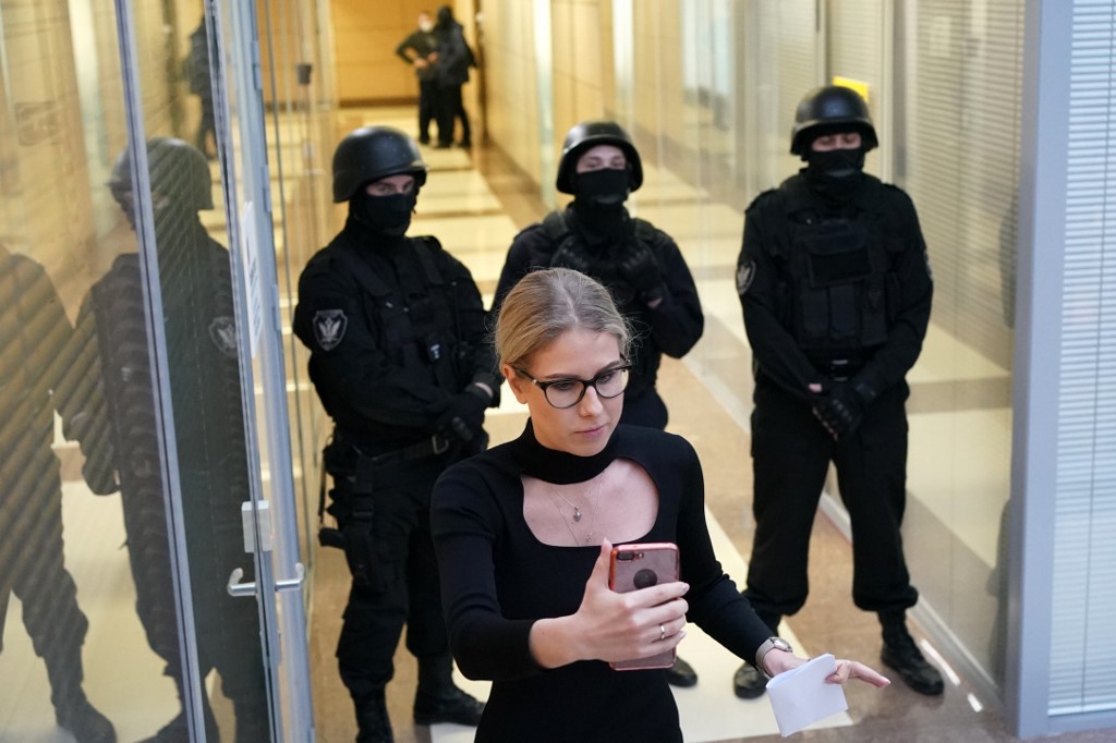 Cette photo a été prise le 26 décembre 2019, montrant la politicienne de l'opposition Lyubov Sobol utilisant son smartphone tout en se tenant devant des agents des forces de l'ordre dans un couloir d'un centre d'affaires à Moscou. (AFP)