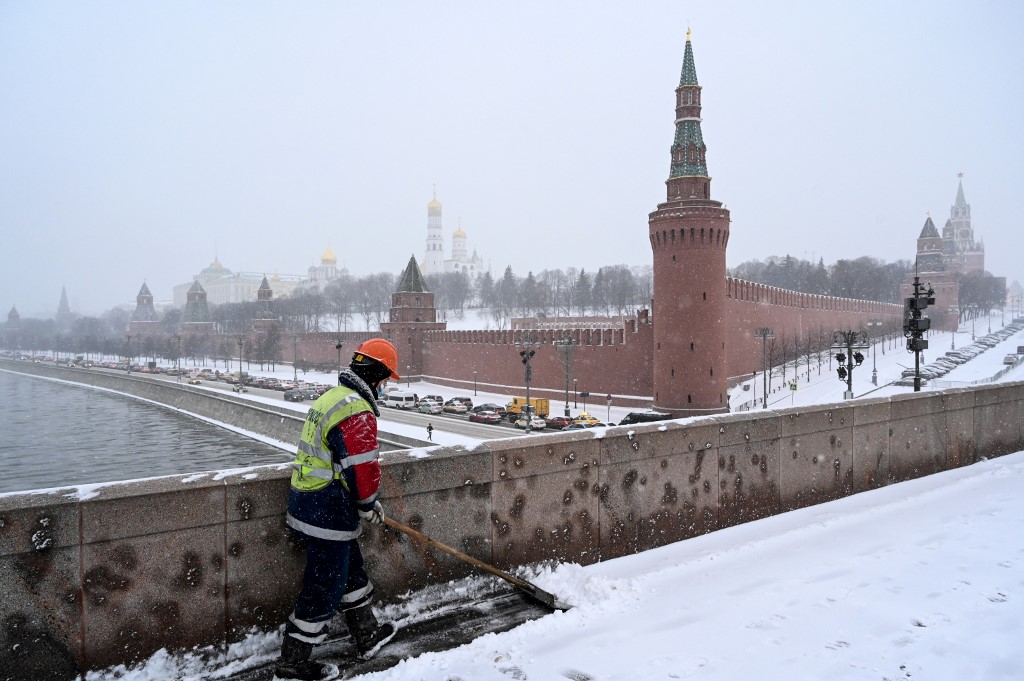 Un travailleur nettoie la neige sur un pont sur la rivière Moskova à l'extérieur du Kremlin lors d'une forte chute de neige à Moscou le 25 décembre 2020. (AFP)