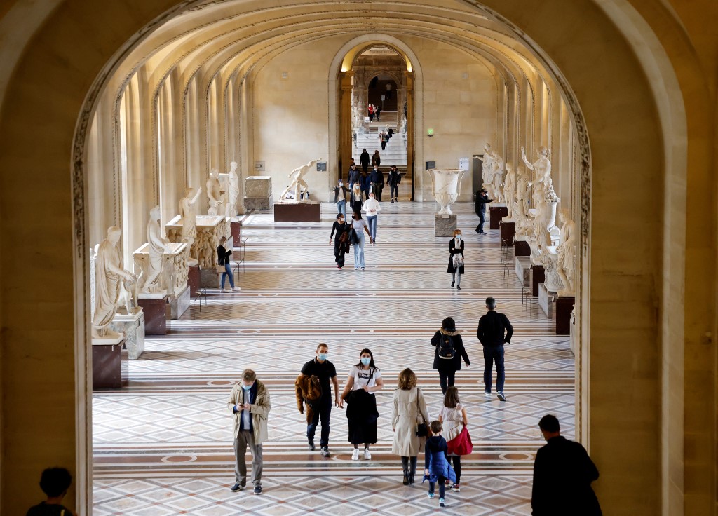 Des visiteurs portant des masques faciaux marchent dans une allée du musée du Louvre, désertée par les touristes en raison de la pandémie de la Covid-19, à Paris, le 14 octobre 2020. (AFP)