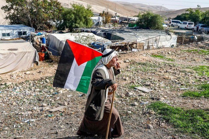 Un Bédouin marche avec un drapeau palestinien dans le village de Khan Al-Ahmar en Cisjordanie occupée par Israël le 29 novembre 2020 (Fichier / AFP)
