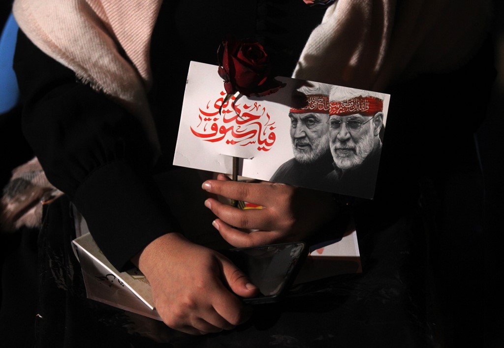 Une femme irakienne porte un portrait du défunt commandant irakien Abu Mahdi al-Muhandis et du commandant iranien Qasem Soleimani à l'aéroport de Bagdad, à Bagdad, le 2 janvier 2021, sur le site de leur meurtre. (AFP)