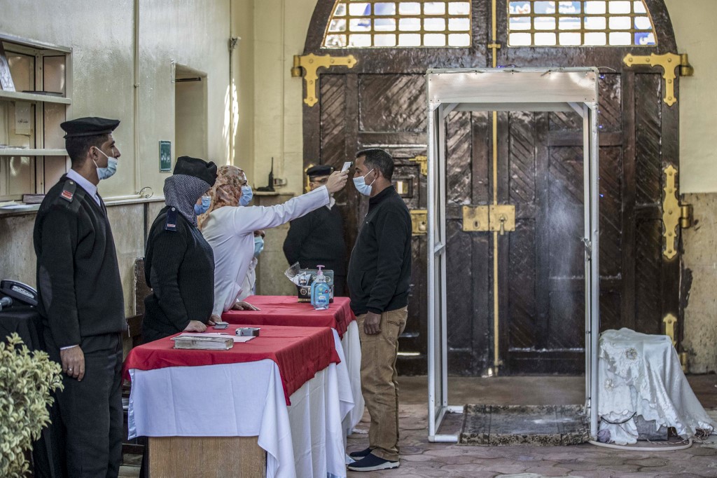 Cette photo prise lors d'une visite guidée par le gouvernement, le 27 décembre 2020, montre une femme mesurant la température corporelle d'un homme, dans le cadre du protocole de dépistage de la pandémie de la Covid-19. (AFP)