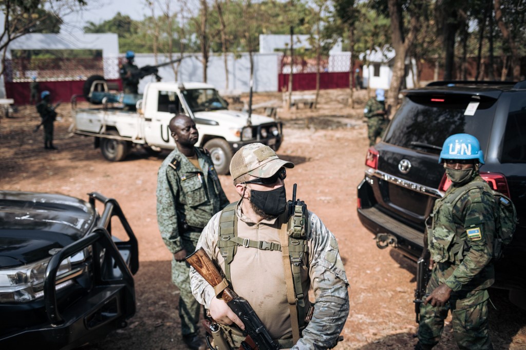 Un soldat de la paix rwandais de la Mission multidimensionnelle intégrée des Nations Unies pour la stabilisation en République centrafricaine (MINUSCA) (D), un garde de sécurité privé russe (C) et un membre de la garde présidentielle (G), montent la garde pendant que Le président Faustin Archange Touadera (non visible) est au bureau de vote du lycée Barthélemy Boganda dans le 1er arrondissement de Bangui, en République centrafricaine (RCA), le 27 décembre 2020, lors de l'élection présidentielle et législative du pays. (AFP)