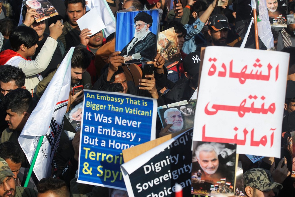 Des manifestants irakiens lèvent une pancarte indiquant «le martyre est notre plus grand rêve» et des portraits du commandant irakien Abu Mahdi al-Muhandis et du commandant des Gardiens de la révolution iranienne Qasem Soleiman. (AFP)