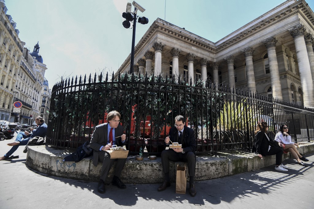 Les gens déjeunent place de la Bourse près du Palais Brongniart, à Paris, le 18 mai 2020. (AFP)