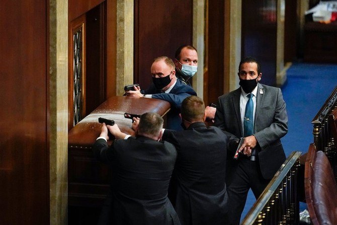 La police du Capitole des États-Unis avec des armes à feu se tient près d'une porte barricadée alors que les manifestants tentent de s'introduire dans la salle de la Chambre du Capitole des États-Unis le mercredi 6 janvier 2021 à Washington. (Photo AP / Andrew Harnik)