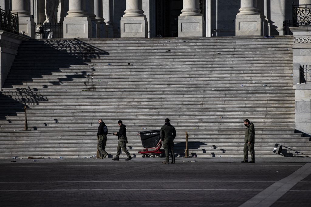Des agents de police examinent les dégâts et les débris laissés sur les marches est du Capitole américain le 7 janvier 2021 à Washington, DC. (AFP)