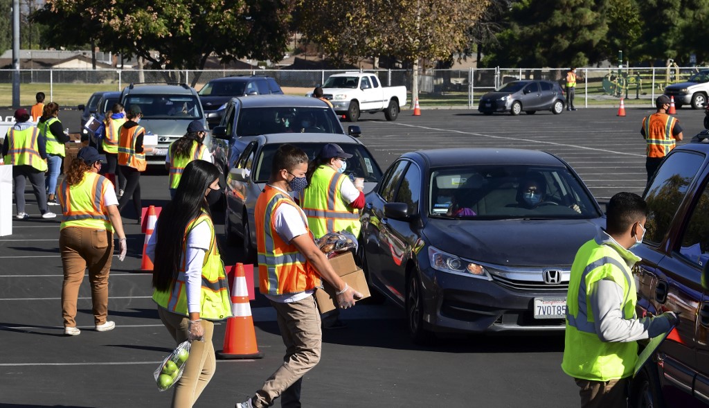 Dans cette photo prise le 4 décembre 2020, la nourriture est chargée alors que les chauffeurs dans leurs véhicules font la queue à leur arrivée à une distribution de nourriture « Let's Feed LA County » organisée par la Los Angeles Food Bank à Hacienda Heights, Californie. (AFP)