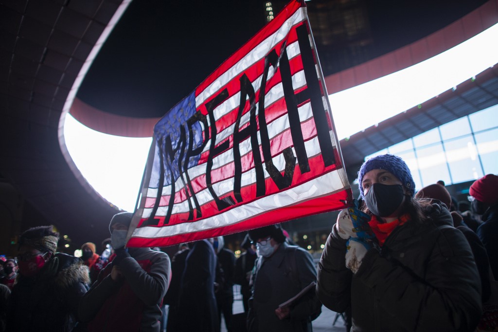 Les manifestants tiennent une banderole appelant à la destitution du président américain Donald Trump lors d'une manifestation devant le Barclays Center de Brooklyn, New York, le 7 janvier 2021, un jour après que la foule pro-Trump a pris d'assaut et saccagé le Capitole. (AFP)