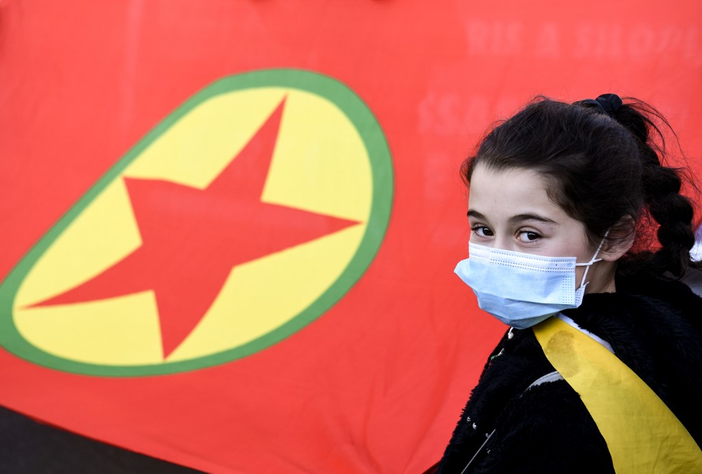 Une fille, portant un masque protecteur, pose à côté d'un drapeau du Parti des travailleurs kurdes (PKK) lors d'une manifestation de partisans kurdes à Paris le 9 janvier 2021, à la mémoire de trois militants kurdes assassinés à Paris. (AFP)