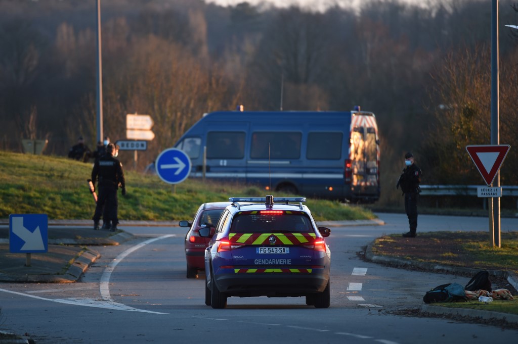 Une voiture de gendarmerie française arrive sur une route pour arrêter l'accès à une fête sauvage, alors que des gendarmes se tiennent autour, à Lieuron à environ 40 km au sud de Rennes, le 1er janvier 2021. (AFP)