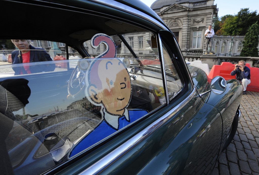 Un homme prend une photo d'un véhicule du rallye automobile "Tintin magazine" le 8 septembre 2013 à Bruxelles. (AFP)