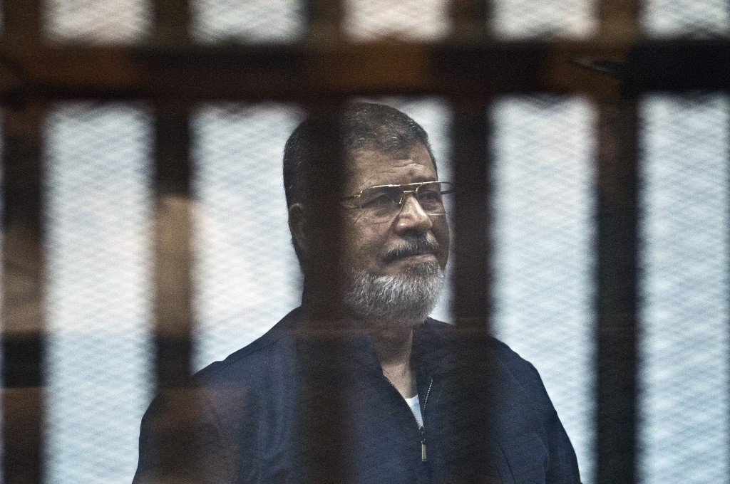 Le président islamiste déchu égyptien Mohamed Morsi se tient derrière le bar. (AFP)