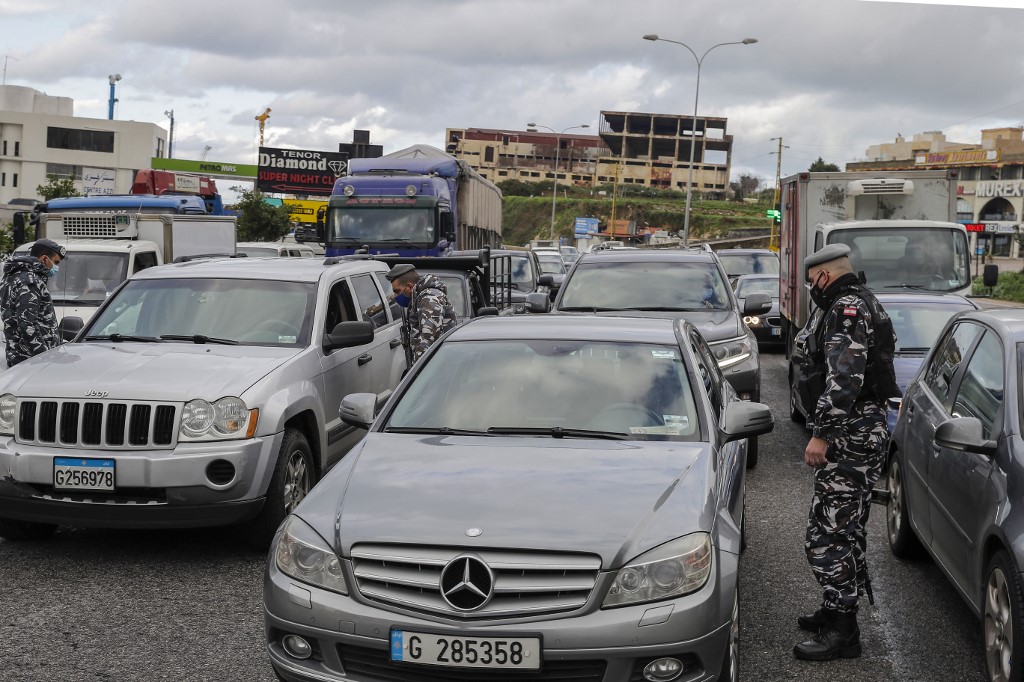Des membres des forces de sécurité libanaises vérifient les documents des citoyens à un point de contrôle COVID-19 près de la ville côtière de Safra sur la route principale Tripoli-Beyrouth. (AFP)