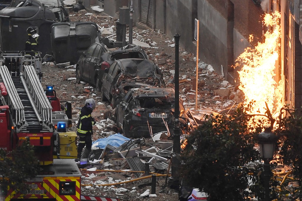 Les pompiers marchent devant un immeuble de Madrid le 20 janvier 2021 après qu'une forte explosion l'ait secoué. (AFP)