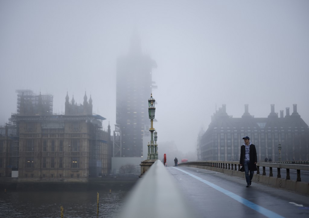 Les piétons traversent le pont de Westminster alors que le brouillard enveloppe la tour Elizabeth, communément connue sous le nom de la cloche, "Big Ben", et le palais de Westminster, qui abrite les chambres du Parlement, à Londres le 8 décembre 2020. (AFP)