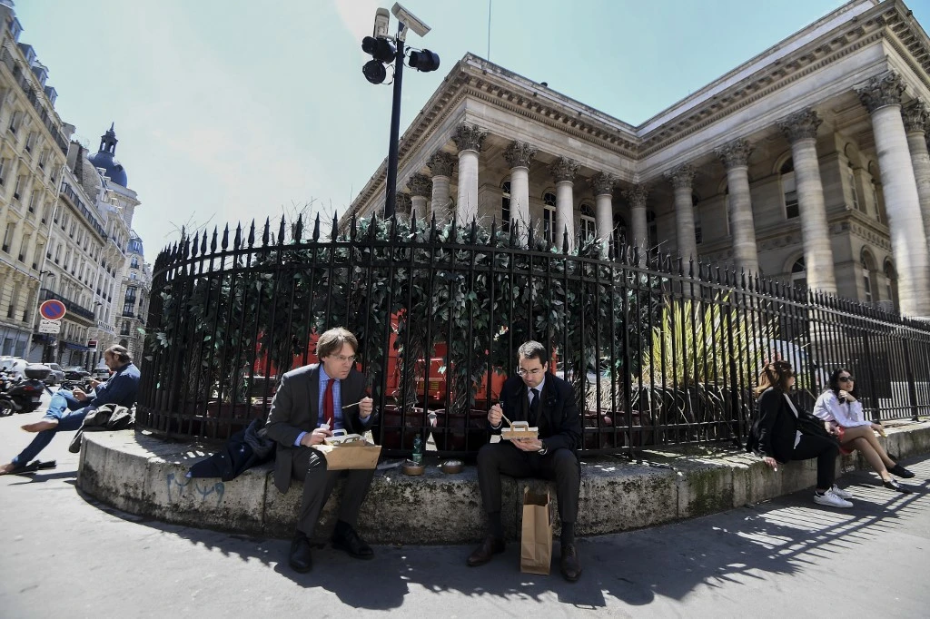 Les gens déjeunent place de la Bourse près du Palais Brongniart, à Paris, le 18 mai 2020. (AFP)