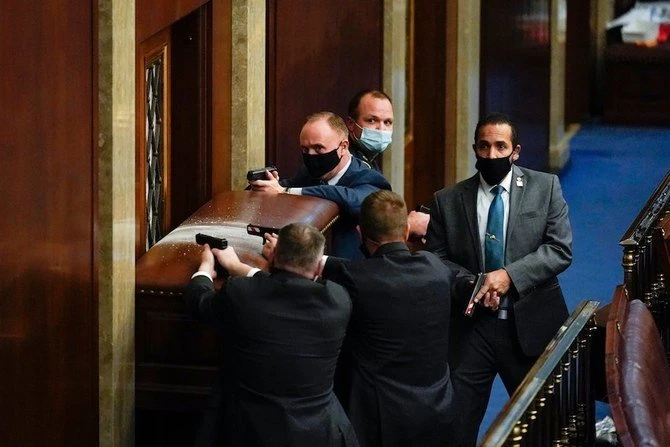 La police du Capitole des États-Unis avec des armes à feu se tient près d'une porte barricadée alors que les manifestants tentent de s'introduire dans la salle de la Chambre du Capitole des États-Unis le mercredi 6 janvier 2021 à Washington. (Photo AP / Andrew Harnik)