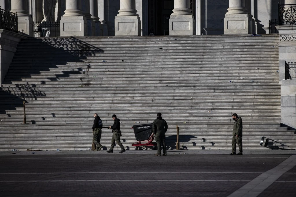 Des agents de police examinent les dégâts et les débris laissés sur les marches est du Capitole américain le 7 janvier 2021 à Washington, DC. (AFP)