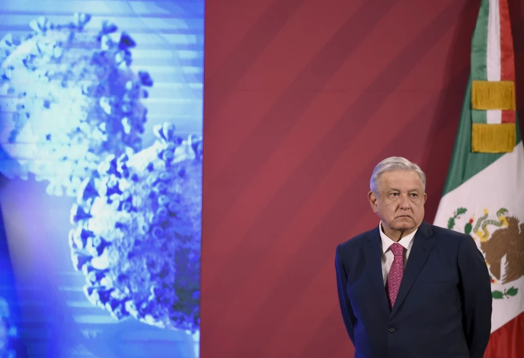 Le président mexicain Andres Manuel Lopez Obrador se tient à côté du drapeau mexicain avant sa conférence de presse quotidienne au Palacio Nacional de Mexico, le 8 décembre 2020. (AFP)