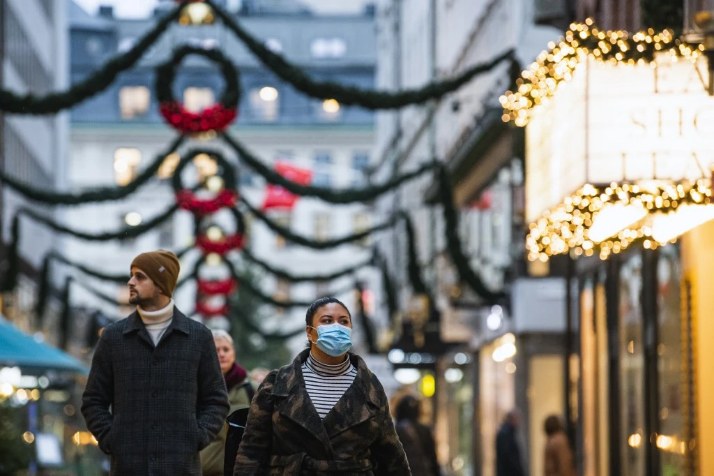 Les gens passent devant les magasins sous les décorations de Noël à Stockholm le 3 décembre 2020, lors de la pandémie du nouveau coronavirus. (AFP)