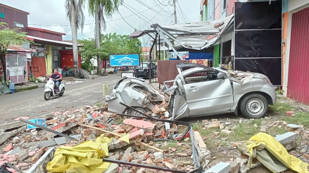 Une voiture détruite se trouve parmi les débris sur le côté d'une rue de Mamuju le 15 janvier 2021, après qu'un tremblement de terre de magnitude 6,2 a secoué l'île de Sulawesi en Indonésie. (AFP)