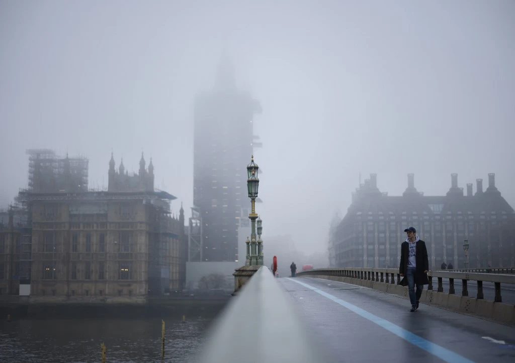 Les piétons traversent le pont de Westminster alors que le brouillard enveloppe la tour Elizabeth, communément connue sous le nom de la cloche, "Big Ben", et le palais de Westminster, qui abrite les chambres du Parlement, à Londres le 8 décembre 2020. (AFP)