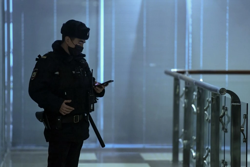 Un policier utilise son smartphone debout dans un couloir d'un centre d'affaires, qui abrite le bureau du chef de l'opposition Alexei Navalny's Anti-Corruption Foundation (FBK), à Moscou. (AFP)