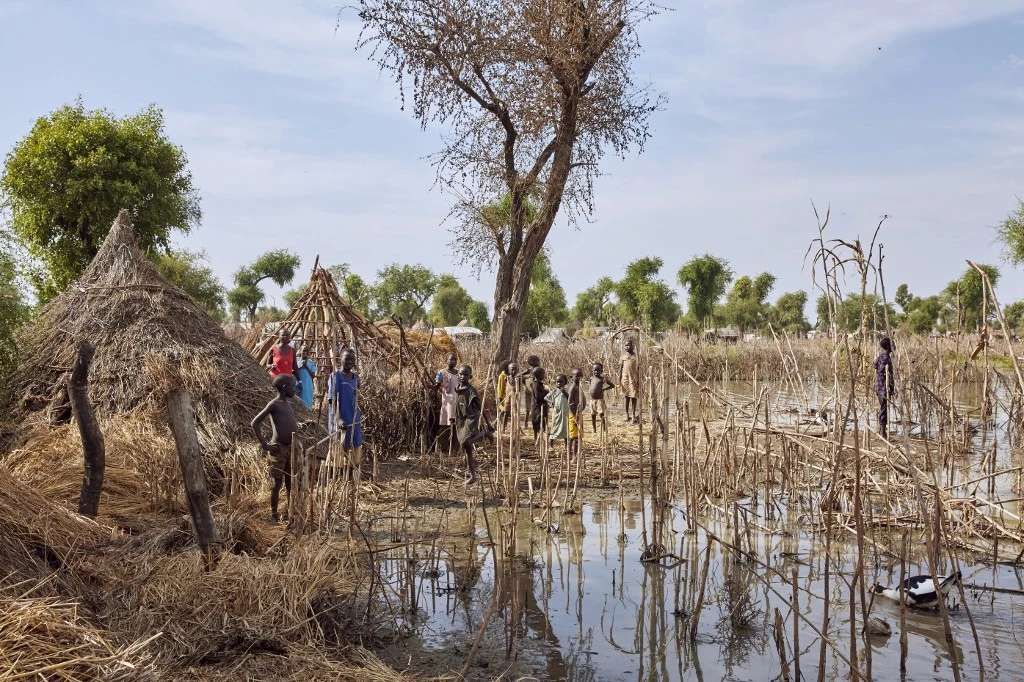 Des enfants se tiennent sur les toits des maisons détruites par les eaux de crue du camp de réfugiés de Yusuf Batir à Maban, au Soudan du Sud, le 25 novembre 2019. (AFP)