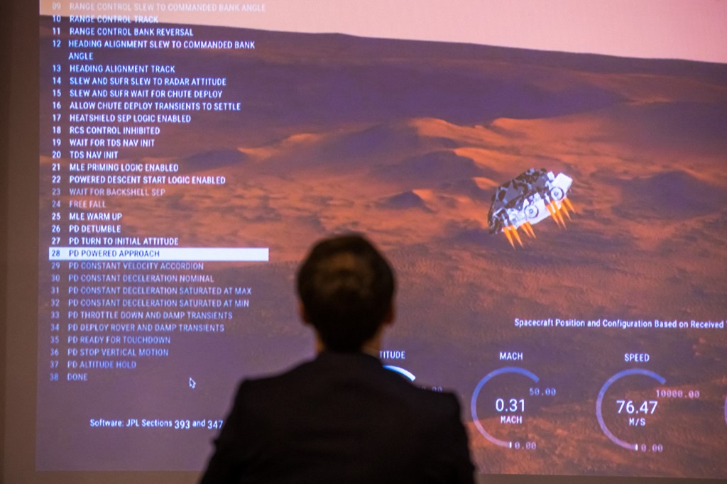 Le président français Emmanuel Macron se tient devant un écran diffusant l'atterrissage du rover Perseverance Mars de la NASA sur la planète Mars, lors d'une visite au Centre national français d'études spatiales (CNES), à Paris, le 18 février 2021. (Photo, AFP)