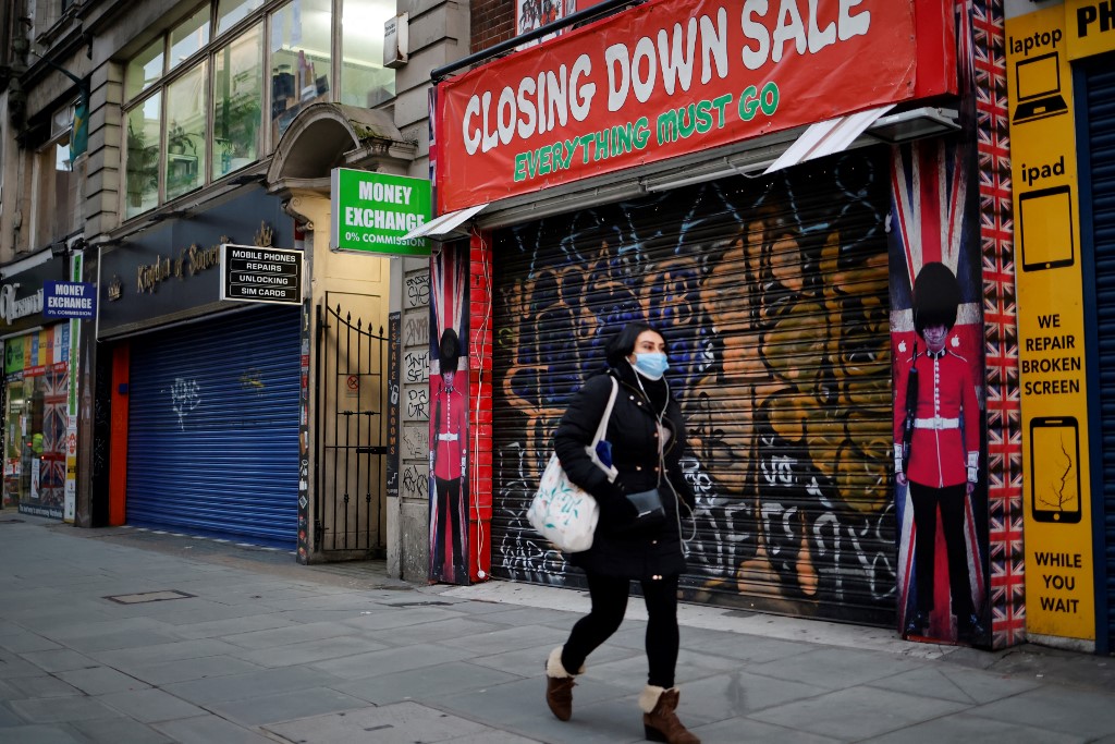 Dans cette photo, un piéton portant un masque facial passe devant une boutique de souvenirs à volets sur Oxford Street, au centre de Londres. (Photo, AFP/Archives)