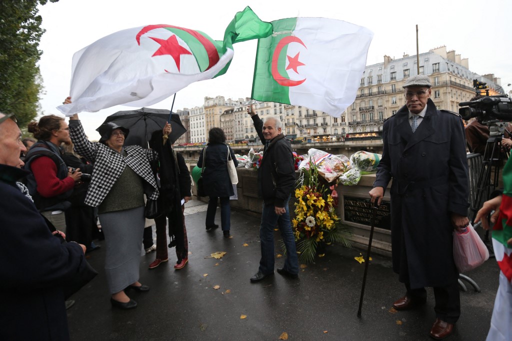 Des gens agitent des drapeaux nationaux algériens le 17 octobre 2012, sur le pont Saint-Michel à Paris, lors d'un rassemblement pour commémorer une manifestation d'Algériens pro-Front de libération nationale (FLN), le 17 octobre 1961 à Paris. (Photo, AFP)