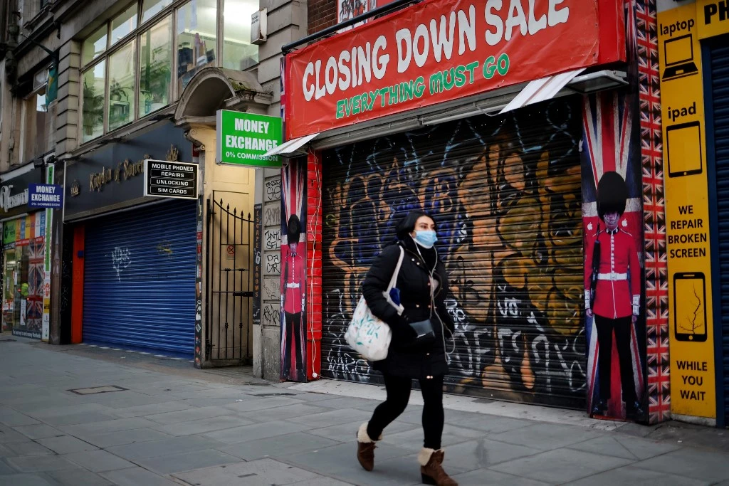 Dans cette photo, un piéton portant un masque facial passe devant une boutique de souvenirs à volets sur Oxford Street, au centre de Londres. (Photo, AFP/Archives)