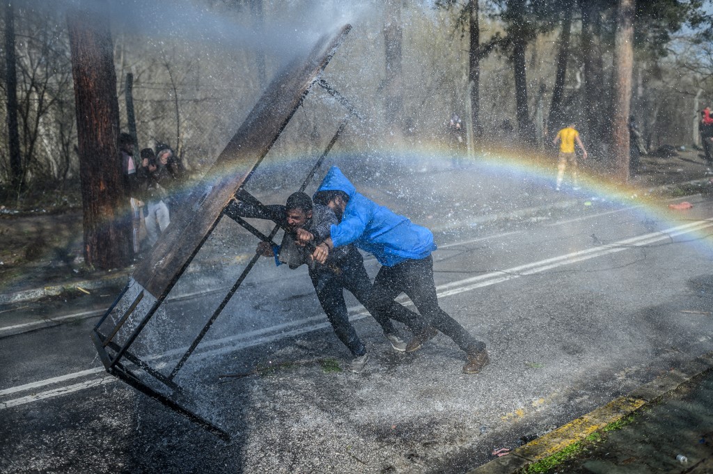 La police grecque utilise des canons à eau pour bloquer des migrants en essayant de briser les clôtures dans la province frontalière turco-grecque d'Edirne, le 7 mars 2020 alors que des camps de fortune ont vu le jour autour de la frontière où des milliers de réfugiés ont été encouragés par la Turquie de partir pour l'Union européenne, dans le but d'obtenir le soutien occidental en Syrie. BULENT KILIC / AFP