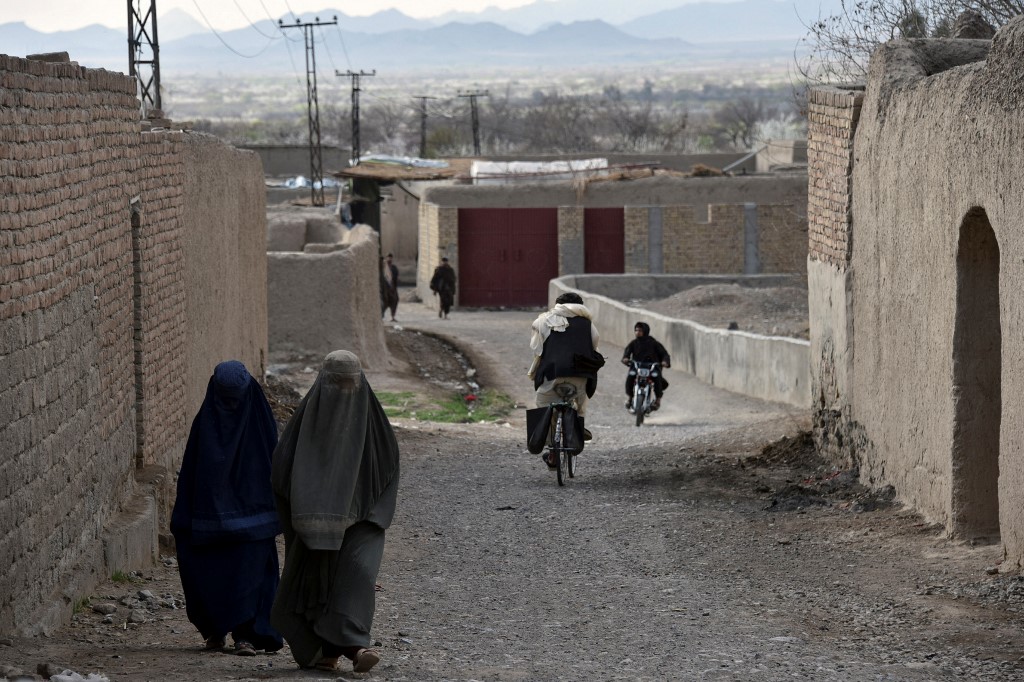 Sur cette photo prise le 22 février 2021, des femmes portant des burqas marchent le long d'une route dans le district d'Arghandab de la province de Kandahar. Les talibans s'en prennent aux ONG venant en aide aux femmes. JAVED TANVEER / AFP