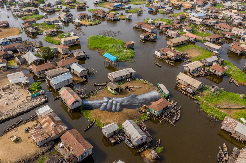 Vue aérienne de l'une des œuvres de l'artiste Guillaume Legros, également connu sous le nom de Saype, de son projet global, Beyond Walls, à Ganvié, Bénin, le 2 mars 2021. Le projet "Beyond Walls" a démarré à Paris devant le Tour Eiffel et a parcouru pendant plusieurs années le monde entier, depuis Andorre, Berlin, Genève, Ouagadougou, Yamoussoukro, Turin, Istanbul et Le Cap avant de rejoindre le village flottant béninois de Ganvie. Yanick Folly / AFP