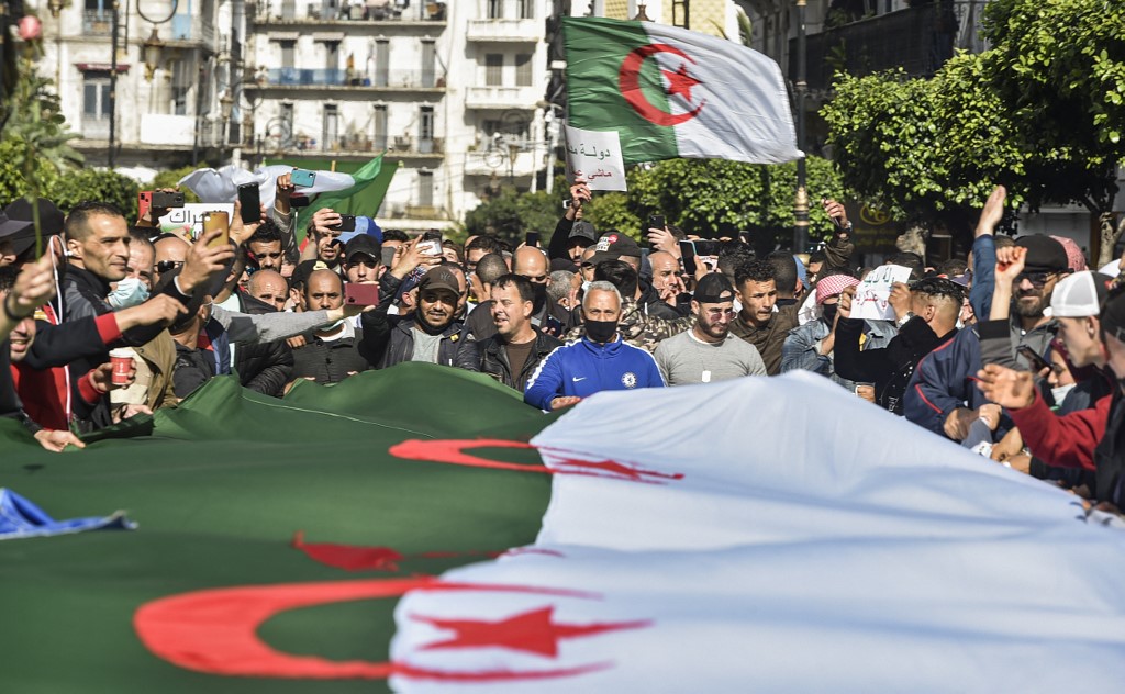 Les Algériens agitent le drapeau national lors d'une manifestation antigouvernementale dans la capitale Alger le 5 mars 2021. Des milliers de personnes ont manifesté à Alger et dans d'autres villes du pays, confirmant la remobilisation du mouvement de protestation Hirak (AFP)