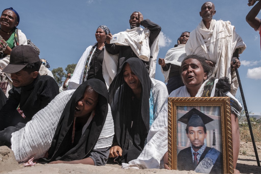 Les gens se tiennent à côté d'une fosse commune contenant les corps de 81 victimes des forces érythréennes et éthiopiennes, tuées lors des violences des mois précédents, dans la ville de Wukro, au nord de Mekele, le 28 février 2021.