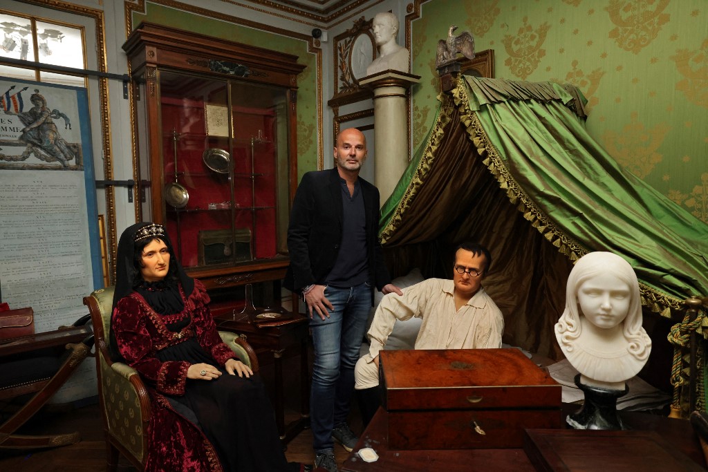 Le collectionneur français Bruno Ledoux (C) pose avec une partie de sa collection privée sur l'empereur Napoléon Ier et des statues de cire représentant Napoléon assis sur son vrai lit et sa mère Letizia Bonaparte, dans son appartement à Paris le 13 mars 2021. THOMAS COEX / AFP