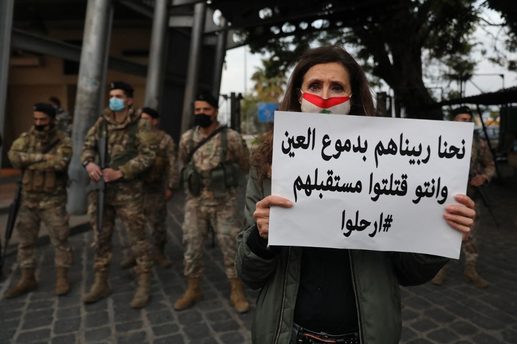 Une femme libanaise tient une pancarte devant des soldats lors d'une manifestation contre la paralysie politique du pays et la profonde crise économique à Beyrouth, à l'occasion de la fête des mères, le 20 mars 2021. "Nous les avons éduqués avec nos larmes et vous leur avez volé leur avenir. Partez!" ANWAR AMRO / AFP