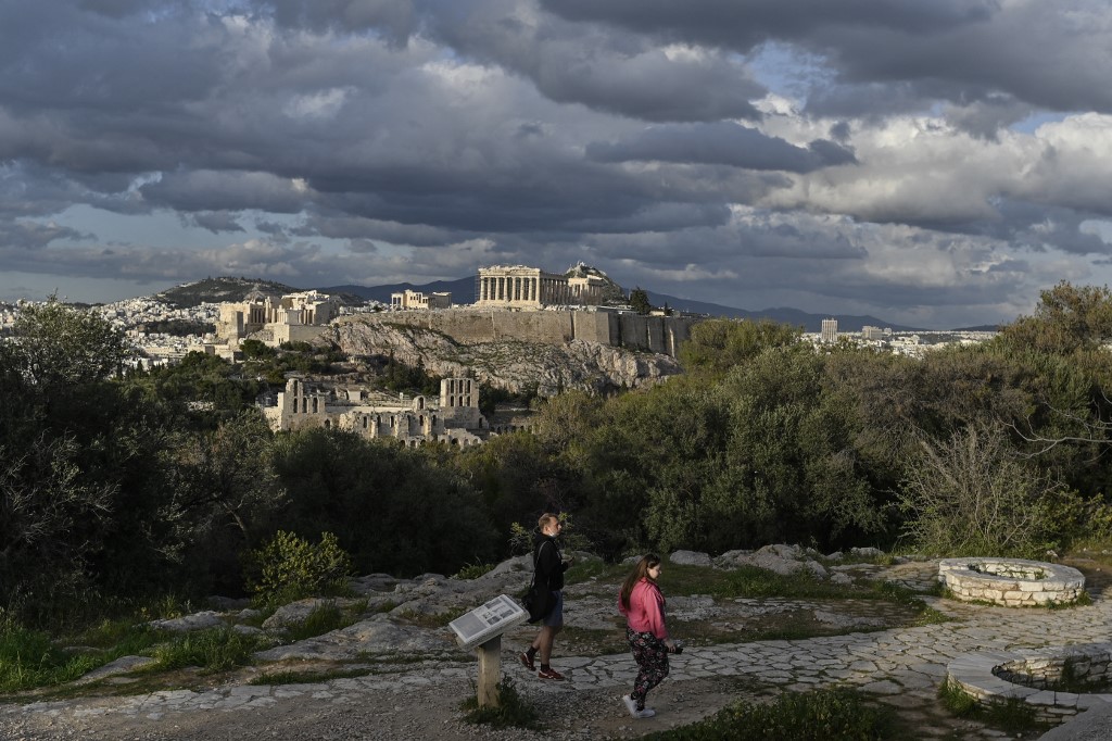 Des visiteurs sur la colline de Filopappou, surplombant l'ancienne Acropole d'Athènes le 22 mars 2021. Louisa GOULIAMAKI / AFP