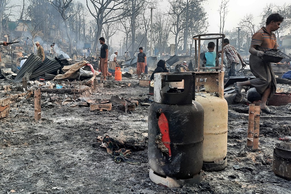 Des gens nettoient des débris dans un camp de réfugiés rohingyas à Ukhia le 23 mars 2021, où un énorme incendie a forcé environ 50000 personnes à fuir. AFP