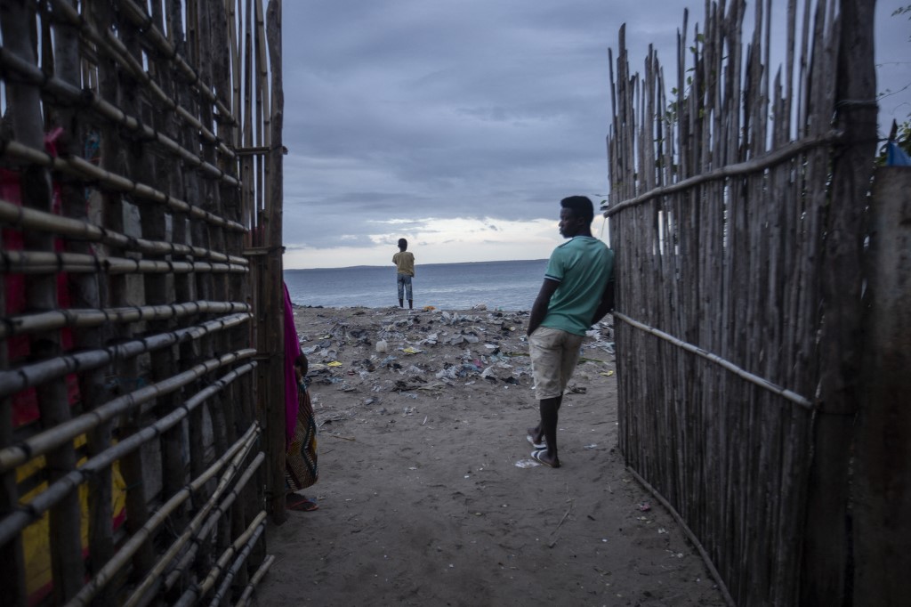 Des hommes surveillent la mer au port du quartier de Paquitequete où des bateaux à voile devraient arriver avec des personnes déplacées des côtes de Palma et d'Afungi après avoir subi des attaques de groupes armés le 30 mars 2021. ALFREDO ZUNIGA / AFP