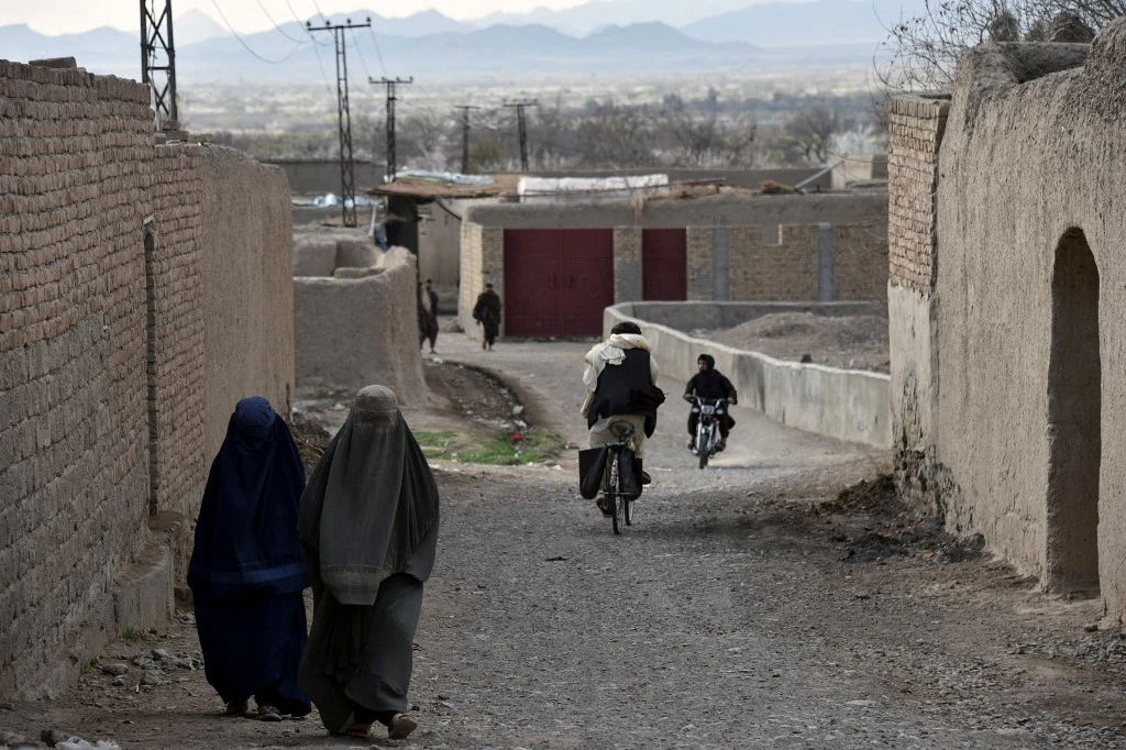 Sur cette photo prise le 22 février 2021, des femmes portant des burqas marchent le long d'une route dans le district d'Arghandab de la province de Kandahar. Les talibans s'en prennent aux ONG venant en aide aux femmes. JAVED TANVEER / AFP