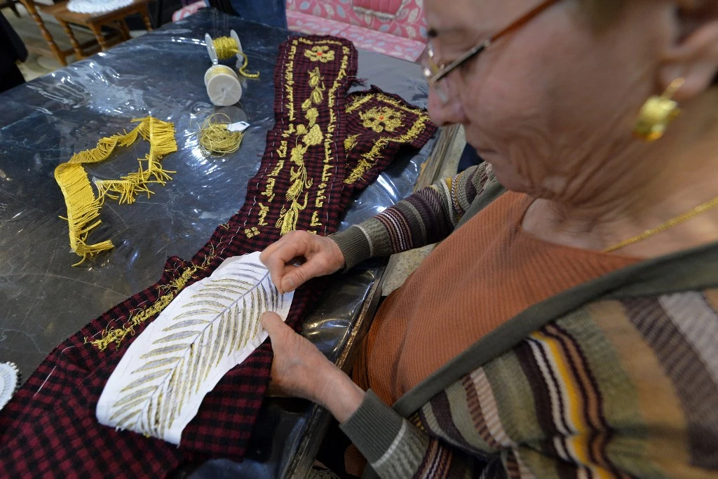 Karjiya Baqtar brode un précieux châle de prière à l'aide de fil d'or, pour l'offrir au pape François lors de sa prochaine visite dans sa ville irakienne de Qaraqosh, dans la province de Ninive, à environ 30 kilomètres de Mossoul, le 4 mars 2021. Zaid AL-OBEIDI / AFP