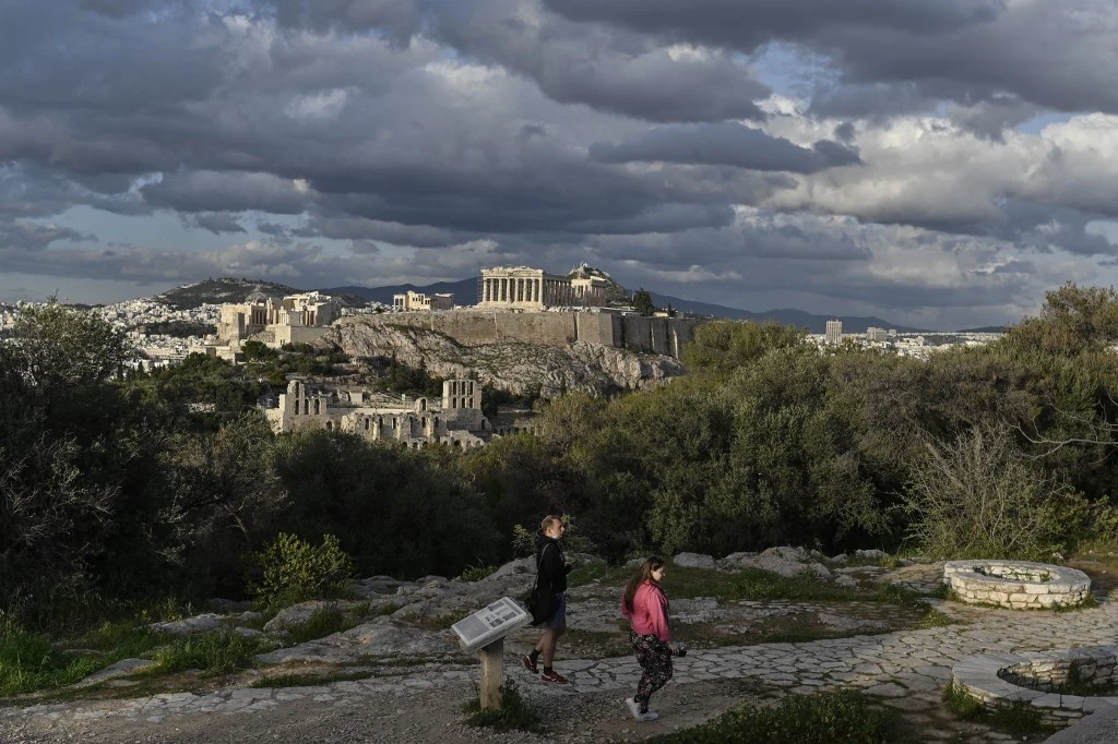 Des visiteurs sur la colline de Filopappou, surplombant l'ancienne Acropole d'Athènes le 22 mars 2021. Louisa GOULIAMAKI / AFP